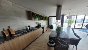 A modern kitchen with a marble countertop, wooden cabinets, and a large window offering a city view. - Skylux Studio Museum of Tomorrow, Rio de Janeiro Wonderful and Safe.  (Centro Rio de Janeiro)