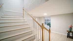 Eine Treppe mit weißen Geländern und Holzsprossen, die zu einer zweiten Etage führt.