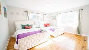 Ein helles Schlafzimmer mit zwei Betten, großen Fenstern und Holzboden.
