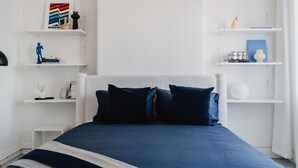 Een slaapkamer met een bed, witte schapenkasten en diverse decoratieve objecten.