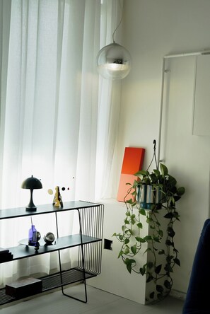 A modern room with a black metal desk, a hanging pendant light, a potted plant, and a red artwork on the wall. - Cozy get away in Collingwood Melbourne with A/C and Wifi (Collingwood)