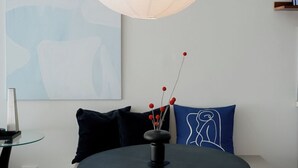 Een ronde tafel met een zwart tafelblad en een gouden voet, omringd door houten stoelen. Daarboven hangt een grote witte hanglamp.