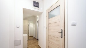 Un pasillo con una puerta de madera, un interruptor de luz y un termostato en la pared.