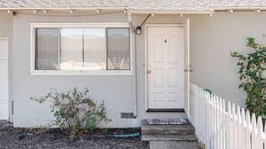 Una casa de un piso con fachada blanca, una puerta principal y una ventana.