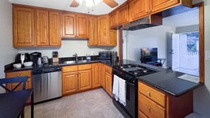 Una cocina con armarios de madera, estufa, lavavajillas y ventilador de techo.