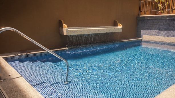 Une piscine dont le fond est carrelé et qui est équipée d’une rambarde métallique.