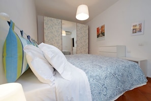 Une chambre à coucher avec un lit, une table de chevet, un miroir et un mur orné de tableaux.
