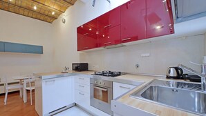 A compact kitchen with white cabinets, a gas stove, an oven, and a sink.