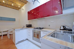 A compact kitchen with white cabinets, a gas stove, an oven, and a sink.