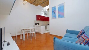 A compact living space with a dining area, kitchenette, and a blue sofa.
