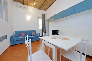 Un salon moderne avec un canapé bleu, une table à manger blanche et des chaises.