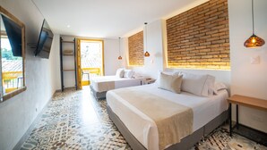 Una habitación de hotel moderna con dos camas, un televisor montado en la pared y una pared decorativa de ladrillo.