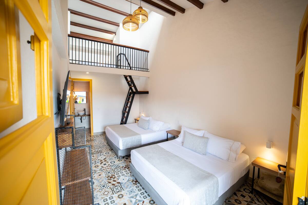 A hotel room with two beds, a staircase, and a balcony.