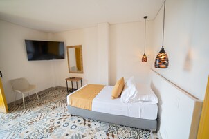 Una camera da letto con un letto, una TV a muro, una sedia e piastrelle decorative.