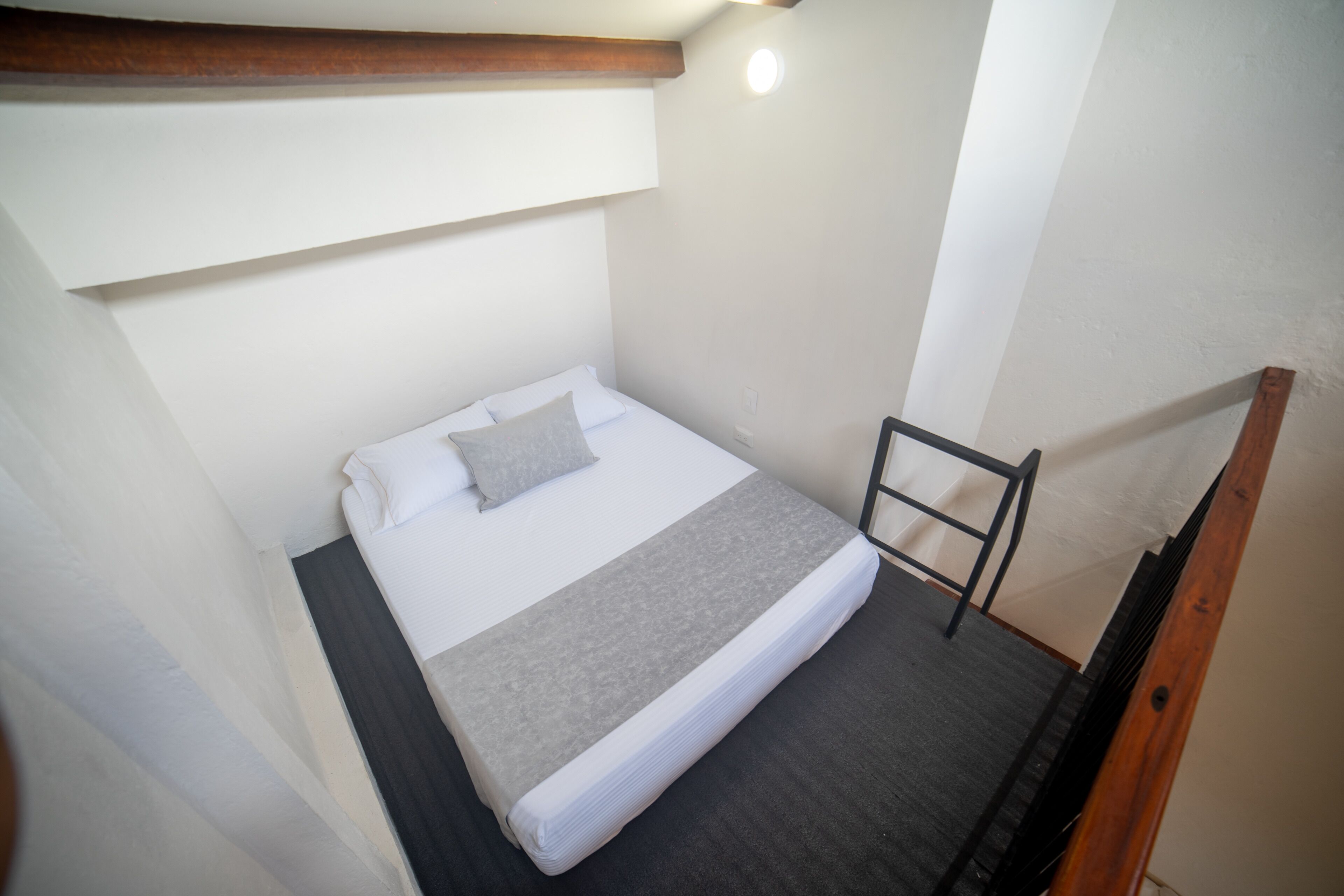 Una habitación pequeña y funcional con una cama individual, cabecera de madera y un diseño sencillo y limpio.