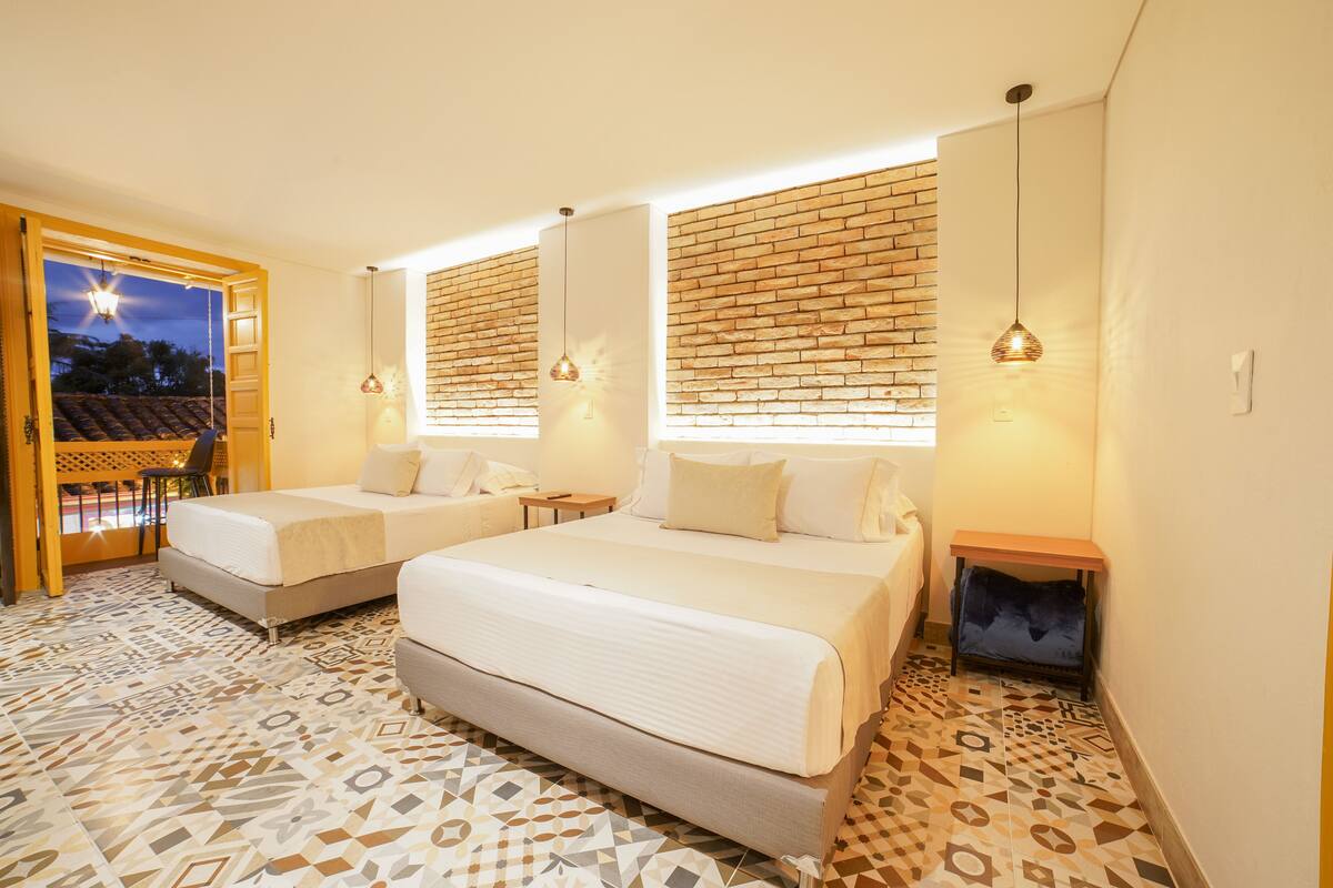 A hotel room with two beds, a brick wall, and a patterned floor.