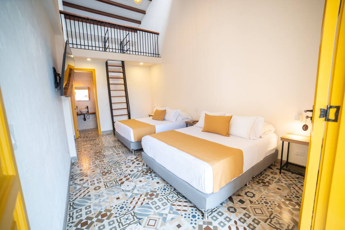 A hotel room with two beds, a staircase, and a tiled floor.