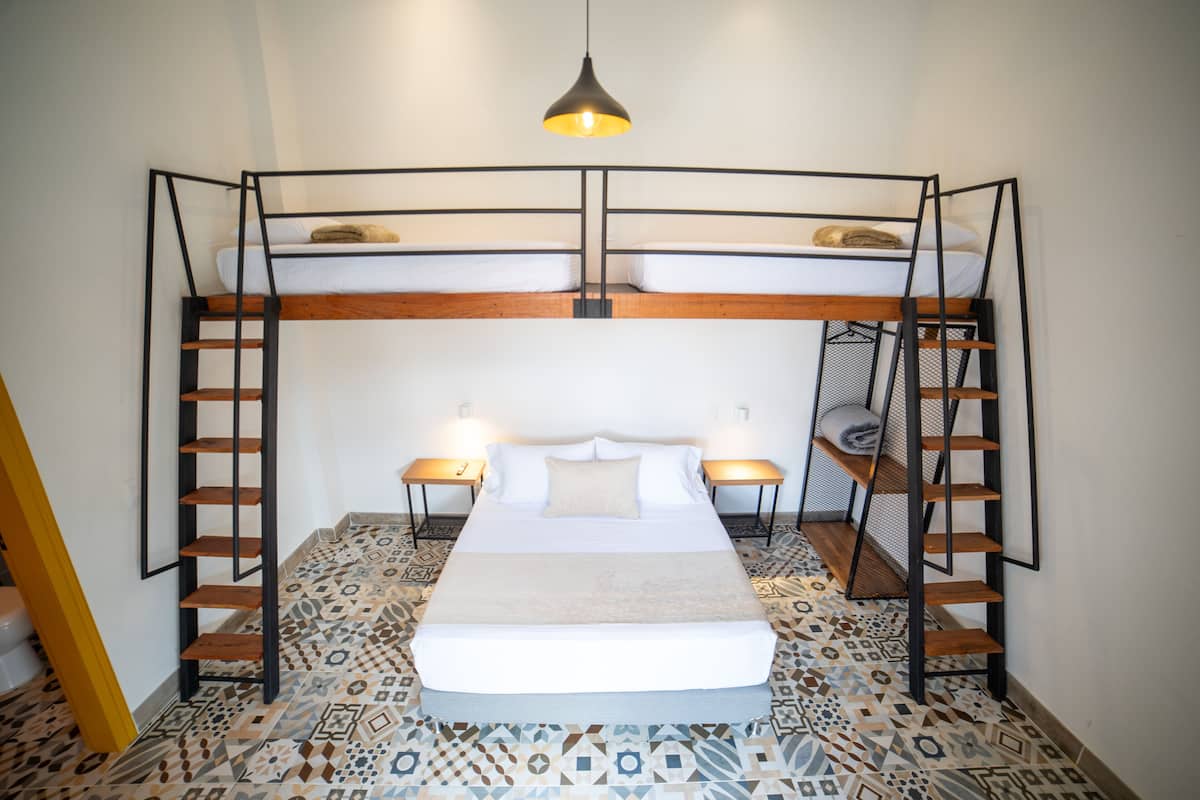 A bunk bed room with a patterned floor, two bedside tables, and a hanging light fixture.