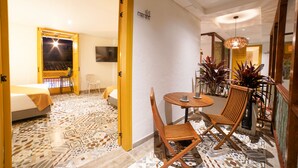 Habitación de hotel con cama, escritorio y silla. Cuenta con un rincón comedor con mesa y sillas.