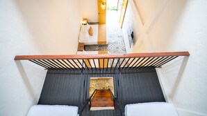 Una escalera que conduce a un dormitorio con cama, mesita de noche y lámpara.