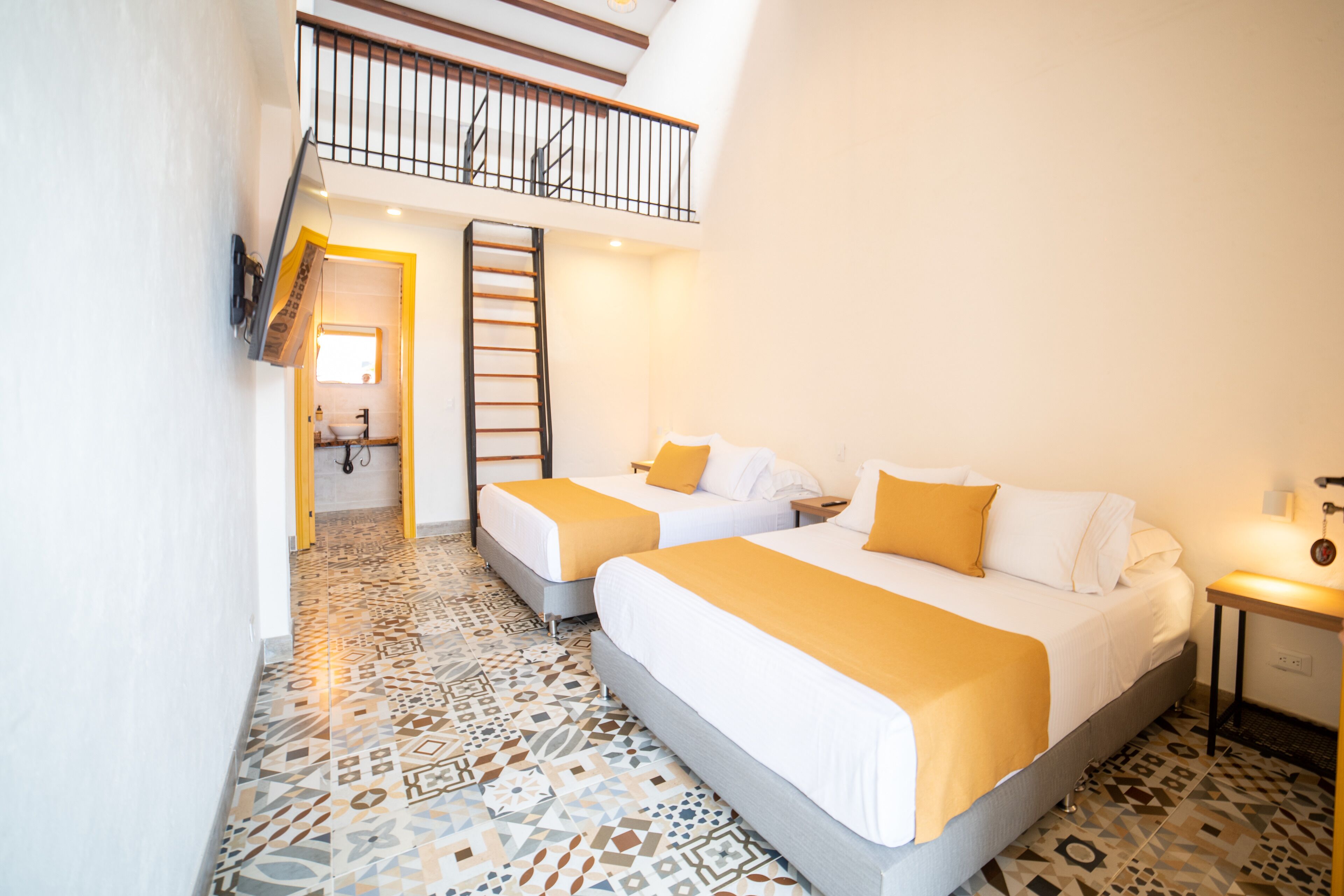 A hotel room with two beds, a staircase, and a patterned floor.