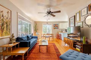 A modern living room with a sofa, coffee table, and TV. There is a dining area with chairs and a table. - Spacious 4bed, super close to UM & Downtown (Missoula)