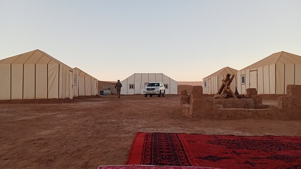 A desert scene with tents and a white vehicle. - BIVOUAC CÔTE-IRIKI (Allougoum)