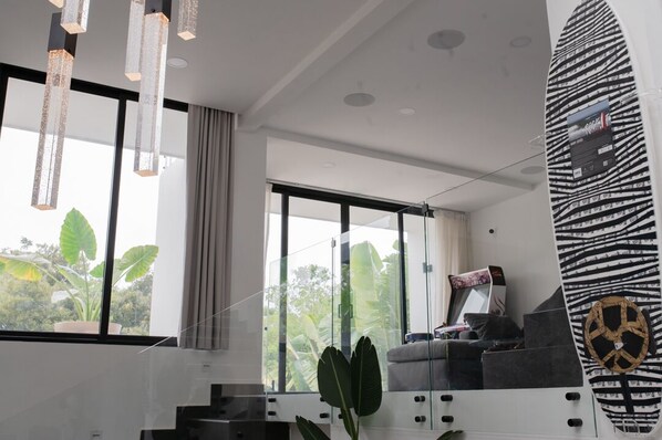 Una sala moderna con ventanas amplias, un sofá y una decoración con una tabla de surf.