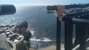 A coastal view with a rocky shoreline, a rope tied to a railing, and a distant view of the ocean. - Hacienda La Ballena  (Cabo San Lucas)