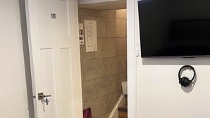 Una habitación de hotel con cama, televisión montada en la pared, puerta con cerradura y escalera que lleva a otra habitación.