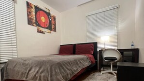 A bedroom with a bed, a desk, a chair, a rug, and a wall with a circular artwork.