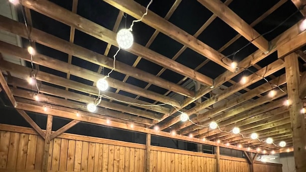 A wooden structure with a sloped roof and string lights.