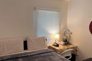 A bedroom with a bed, a nightstand with a lamp, and a window with blinds. - #1(5* Room PRIME LOCALITy WPG Jets {Nr Polo Park} (Winnipeg)