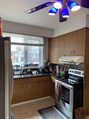 A kitchen with wooden cabinets, a stove, and a window with blinds. - #1(5* Room PRIME LOCALITy WPG Jets {Nr Polo Park} (Winnipeg)