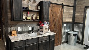 A kitchen with dark wood cabinets, a granite countertop, a coffee maker, and a sink.