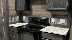 A kitchen with dark wooden cabinets, a black stove, and granite countertops.