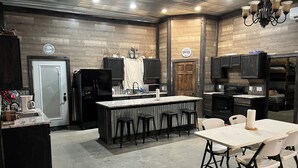 A compact kitchen with a central island, dark cabinetry, and a dining area with a table and chairs.