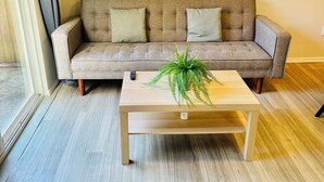 Uma sala de estar com um sofá, uma mesa de centro e uma planta.