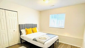 Quarto com cama, janela, luminária no teto e guarda-roupa.