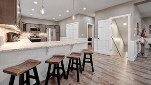 Una cocina moderna con una isla grande, taburetes de madera e iluminación empotrada.