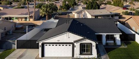 A residential house with a garage, a well-maintained lawn, and a mountainous backdrop.