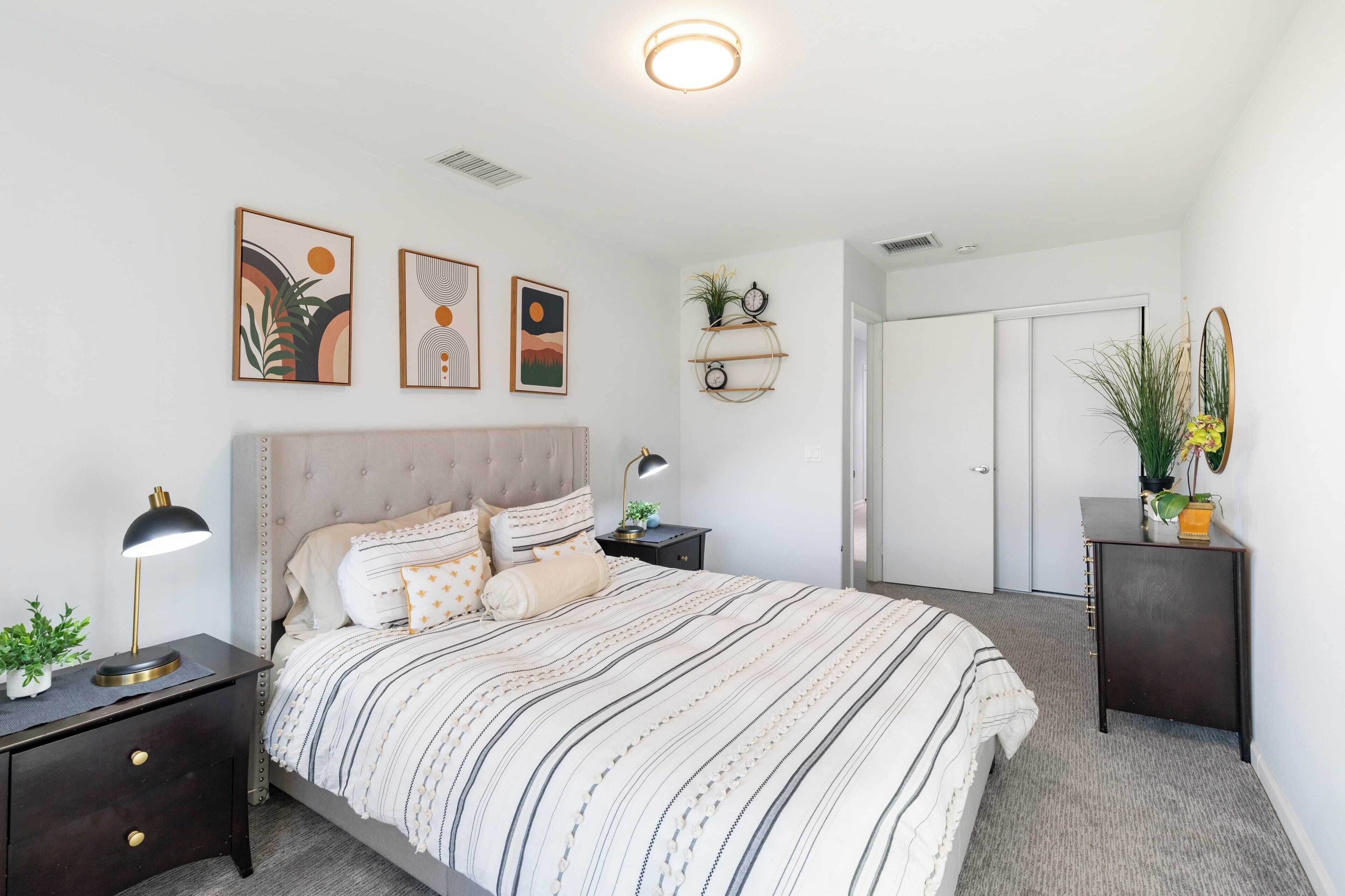A bedroom with a bed, nightstands, a wall-mounted shelf, and a door.