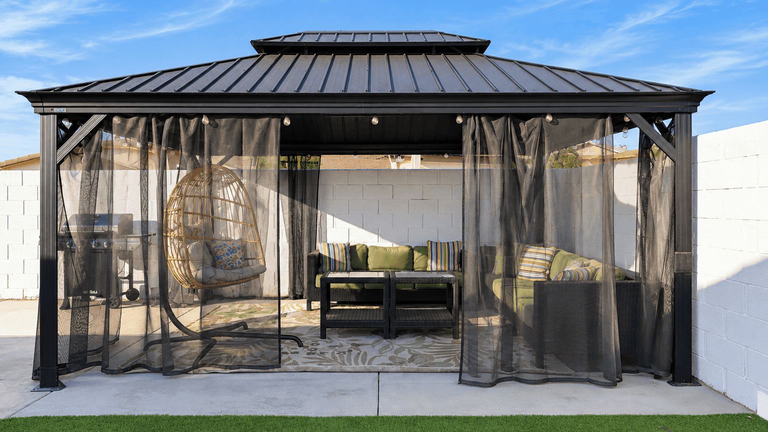 Een overdekt terras met een pergola, een comfortabele bank en een kamerjas.