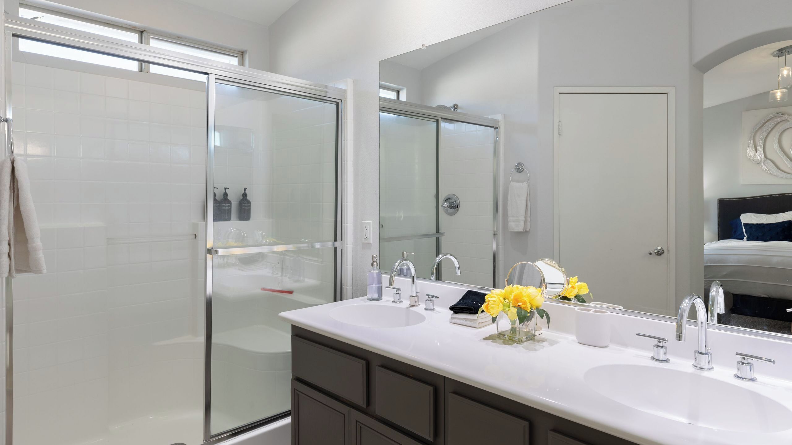 Une salle de bain moderne avec un grand miroir, deux lavabos, une cabine de douche et un porte-serviettes apparent.