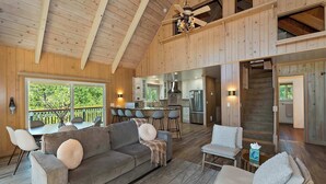 A spacious living area with a large sofa, a dining table, and a kitchen in the background. - Casa Del Lago Spacious 4 Story Gated Home (Lake Arrowhead)