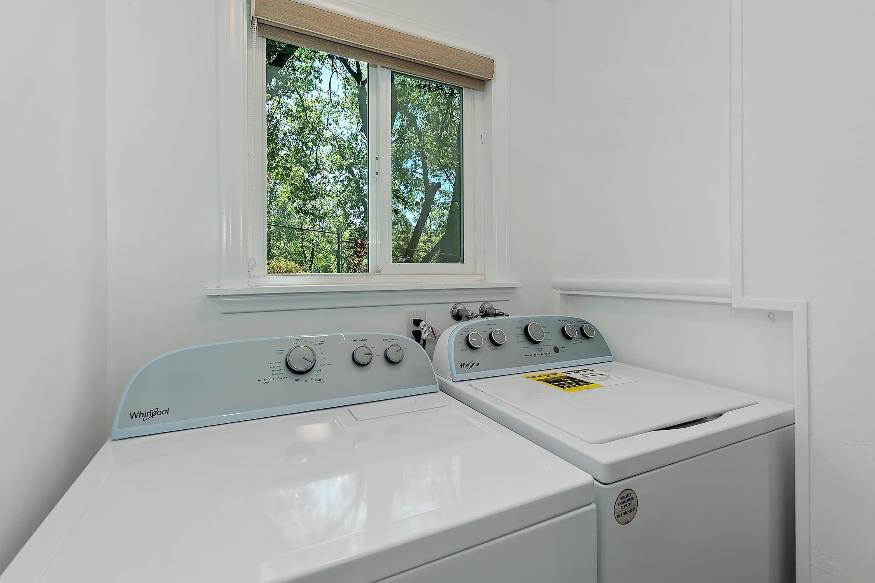 A front-loading Whirlpool washer with a control panel, a window above it, and a white wall.