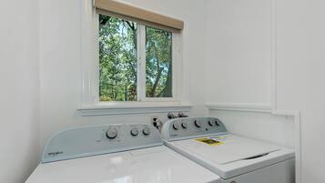 A front-loading Whirlpool washer with a control panel, a window above it, and a white wall.