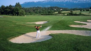 Ein Golfplatz mit Sandfängen und freiem Blick auf ferne Berge.