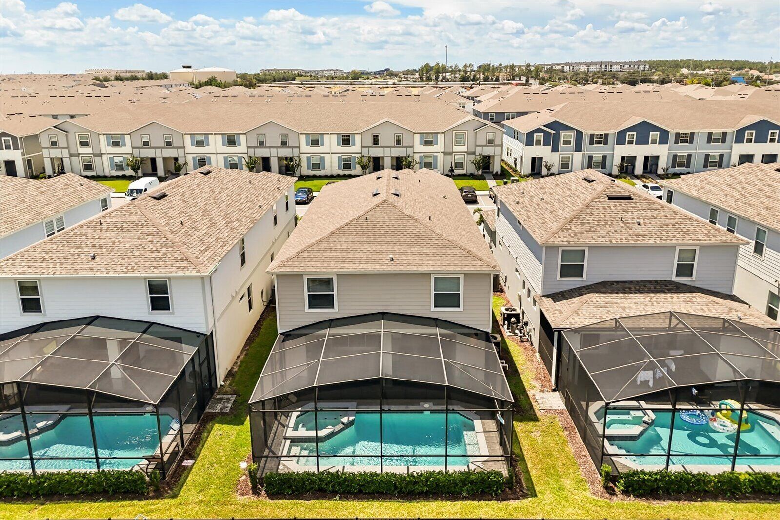 A residential area with multiple two-story houses, each with a covered outdoor swimming pool.