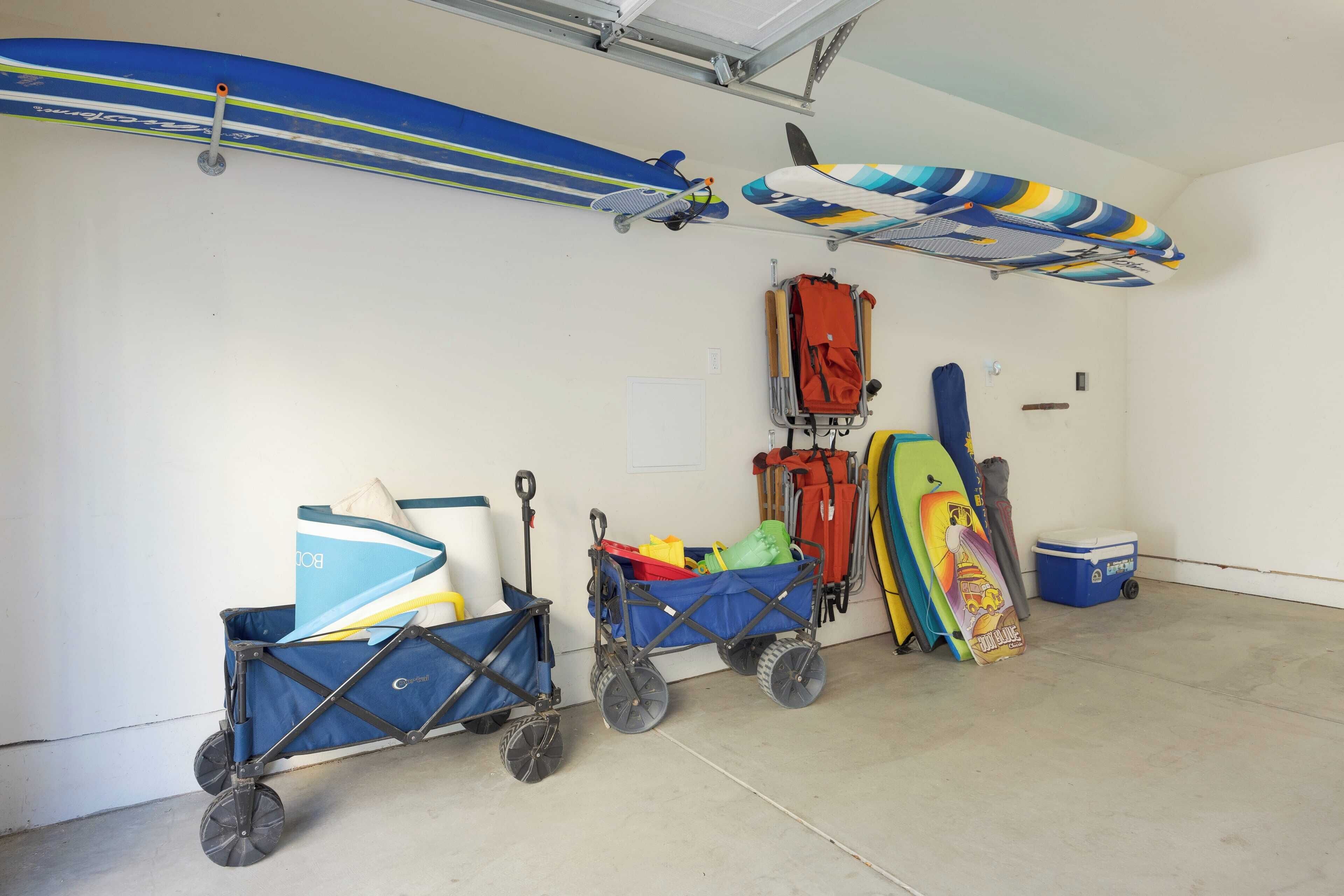 A garage with surfboards, a stroller, and a cooler.